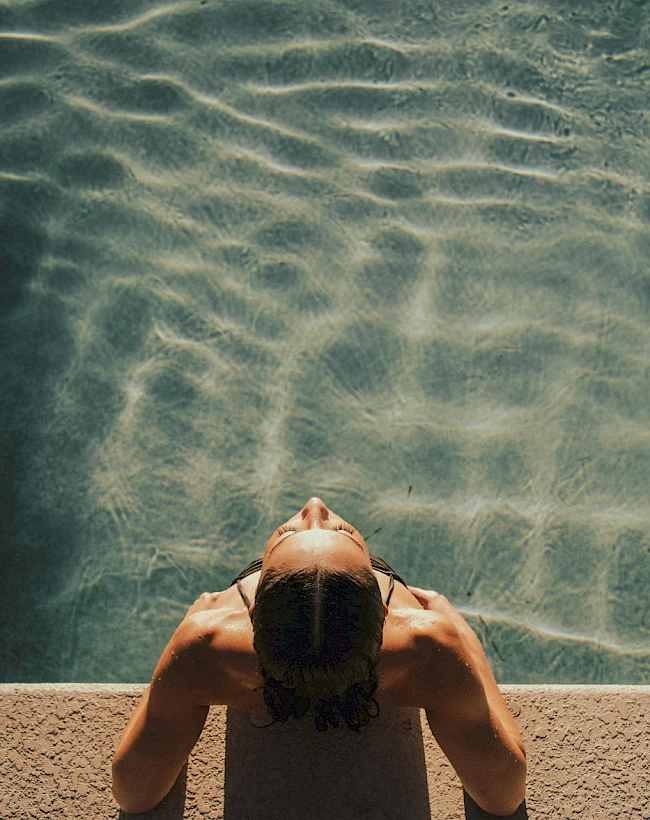 Woman in a pool enjoying the evening sun on her face.