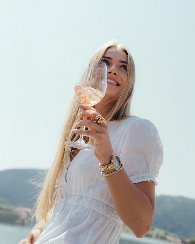 Woman with a drink by lake Schliersee with a view from the lakeside hotel.