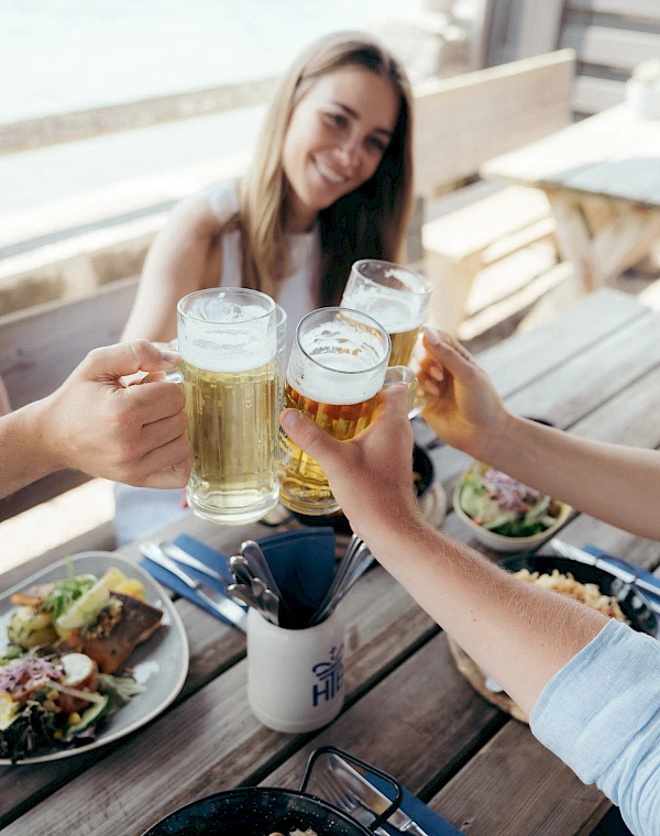 Group toasts with beer in a beer garden while enjoying a hearty meal.