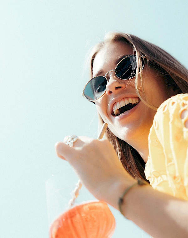 Happy woman against blue sky with drink in hand