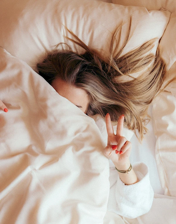 Woman in a cosy bed at the lakeside hotel Schlierseer Hof