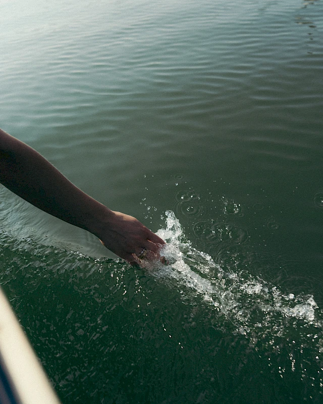 Hand, die vom Boot aus ins Wasser der Schliersees greift