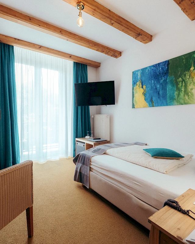 Overview of single room with bed, TV & colourful details