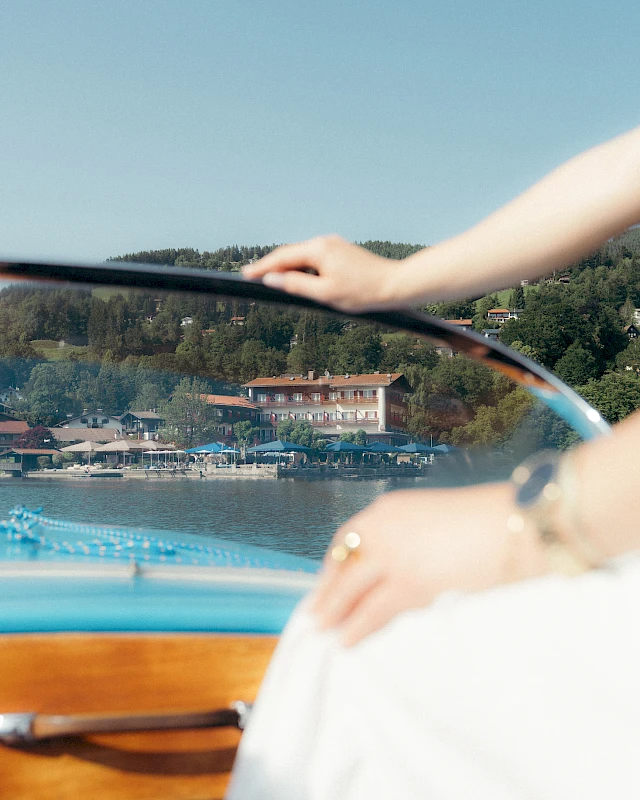 Woman in a boat on Lake Schliersee with a view of the lakeside hotel Schlierseer Hof