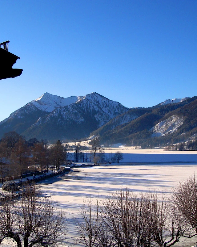 Woman reading a magazine while enjoying a cool drink in the sun, sitting on comfortable lounge furniture at Lake Schliersee.